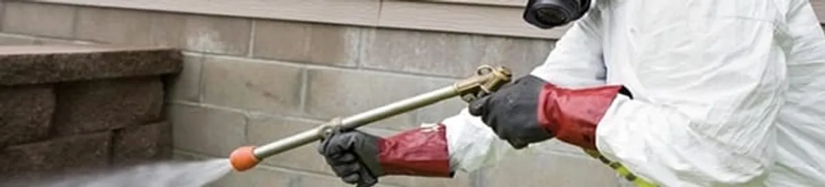 Pest control technician applying exterior insect treatment along a home foundation in Hialeah, FL