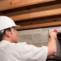 Termite inspection technician checking a basement wall and framing for termite activity in Hialeah, FL