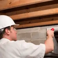 Termite inspection technician checking a basement wall and framing for termite activity in Hialeah, FL